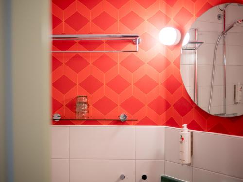 a bathroom with a mirror and a red wall at Good Morning Jönköping in Jönköping