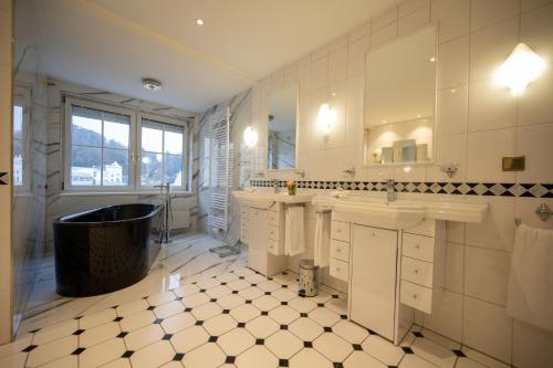 a bathroom with a tub and a sink and a mirror at Hotel Admiral am Kurpark in Baden