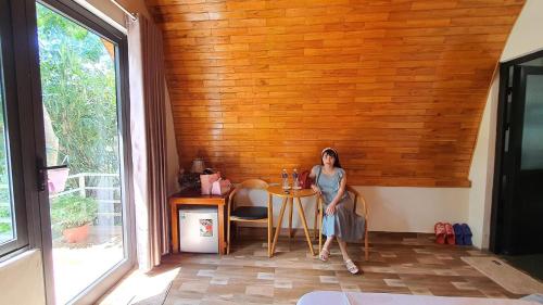 a woman sitting at a table in a room at Areca Bungalow in Phong Nha
