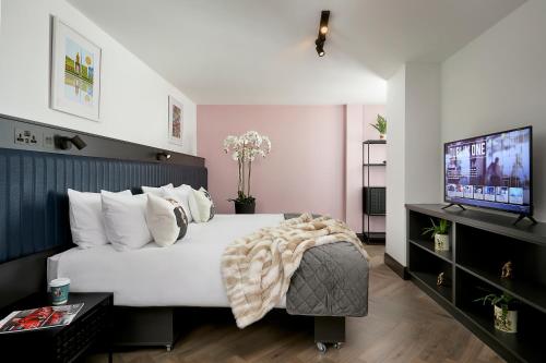 um quarto com uma cama branca e uma televisão de ecrã plano em Dublin One em Dublin