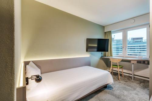 een hotelkamer met een bed, een bureau en een raam bij flexymotel Wil in Wil