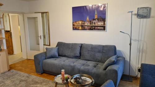 a living room with a blue couch and a painting at PEMATRA Ferienwohnung Seeschwalbe in Travemünde