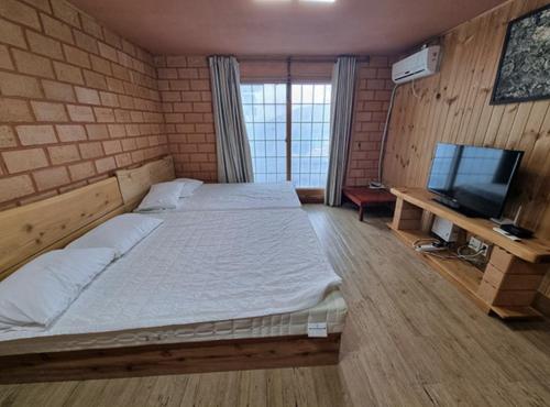 a bedroom with a large bed and a television at Joy Red Clay Resort in Jeju