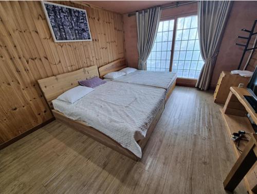 a bedroom with a bed in a wooden room at Joy Red Clay Resort in Jeju