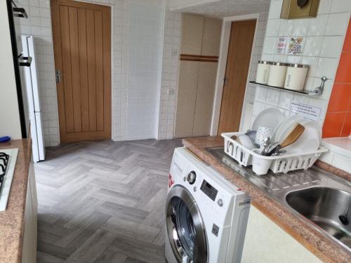 a kitchen with a washing machine and a sink at Modern 3 bedroom house, 3 Bathroom, secure parking, Wi-Fi & Garden in Leeds