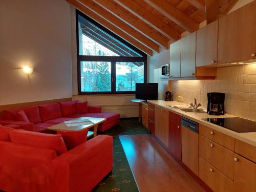 a living room with a red couch and a kitchen at Landhaus Gerber in Lermoos