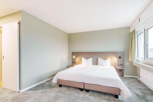 a bedroom with a large white bed and a window at flexymotel Wil in Wil