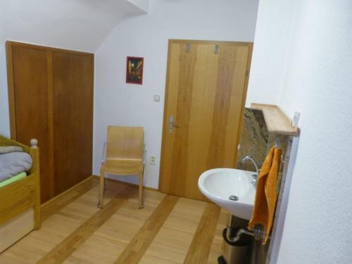 łazienka z umywalką, łóżkiem i krzesłem w obiekcie Ferienhaus auf dem Gries 17 w mieście Schmalkalden