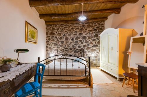 - une chambre avec un lit et un mur en pierre dans l'établissement Antica dimora, à Paulilatino