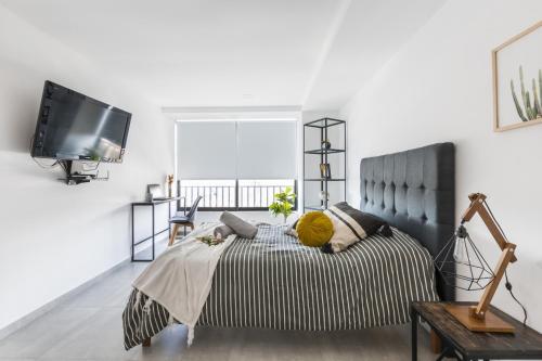 ein Schlafzimmer mit einem Bett und einem TV an der Wand in der Unterkunft Central Balbuena Apartments in Guadalajara