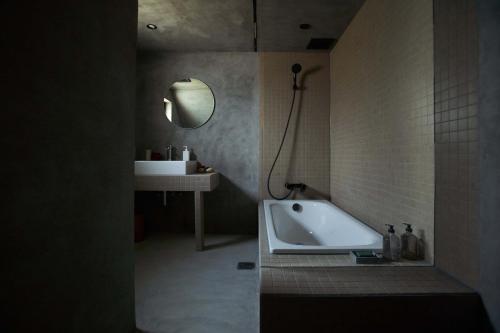 a bathroom with a tub and a sink and a mirror at WORM in Awaji