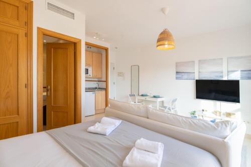 a white bed with two white towels on top of it at Renthas Añoreta Golf Beach in Torre de Benagalbón