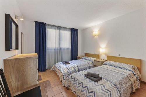 Dos camas en una habitación de hotel con cortinas azules. en Apartamento Playa del Reducto, en Arrecife