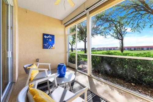 un patio con mesa, sillas y una ventana grande en Beautiful 2 bedroom condo w/ Golf Membership Included en Naples