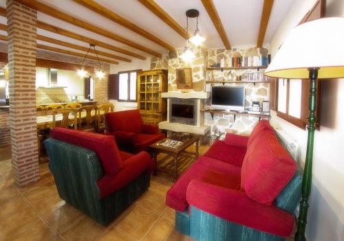 a living room with red chairs and a fireplace at Casa Rural El Gorgocil in Puente del Congosto