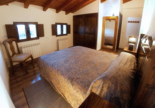 ein Schlafzimmer mit einem großen Bett und einem Stuhl in der Unterkunft Casa Rural El Gorgocil in Puente del Congosto