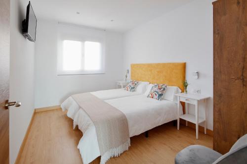 a white bedroom with a large white bed and a window at Balcón de Gijón Apartamentos Boutique in Gijón