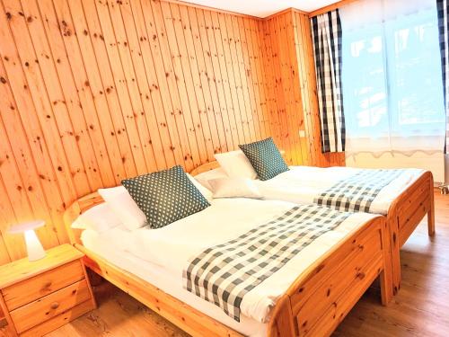 a bedroom with two beds in a wooden wall at Ferienwohnungen Wallis - Randa bei Zermatt in Randa