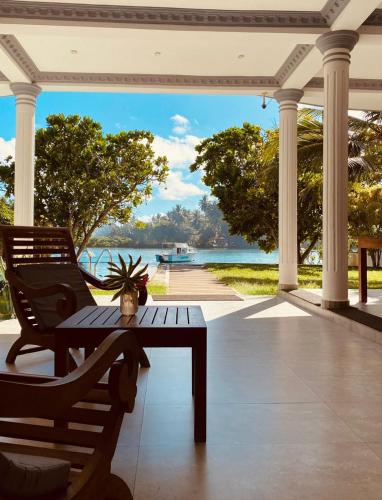 a porch with a bench and a table with a view of the water at Villa Riverside in Aluthgama