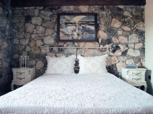 una camera da letto con un letto e una parete in pietra di Spacious rustic country house with sea view a Marónia