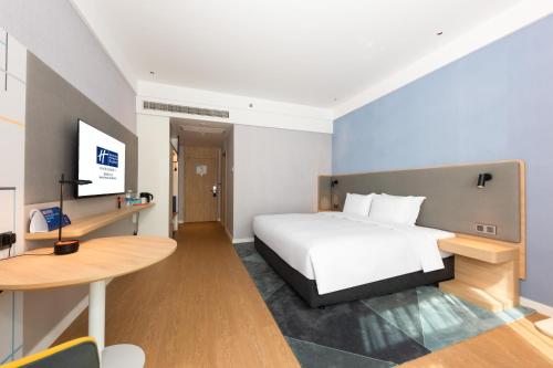 a bedroom with a bed and a desk and a table at Holiday Inn Express Nanchang Riverside by IHG in Nanchang