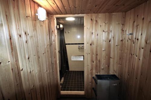 a bathroom with wooden walls and a trash can at RIBO Apartment Arctic in Kiruna
