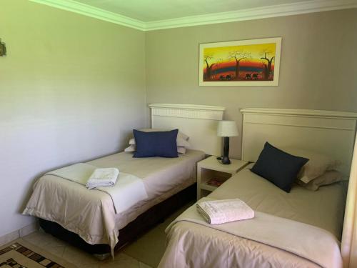 two beds in a room with two pillows at Dobbs Lodge in Centurion