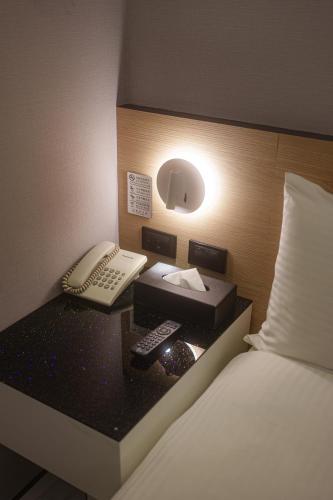 a hotel room with a bed and a phone and a bed gmaxwell gmaxwell at HUB HOTEL Tucheng in Tucheng