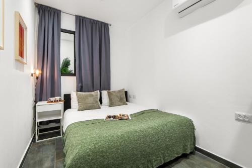 a bedroom with a bed with a green blanket and a window at Renovated apt on Frishman beach with Bomb Shelter M8 in Tel Aviv