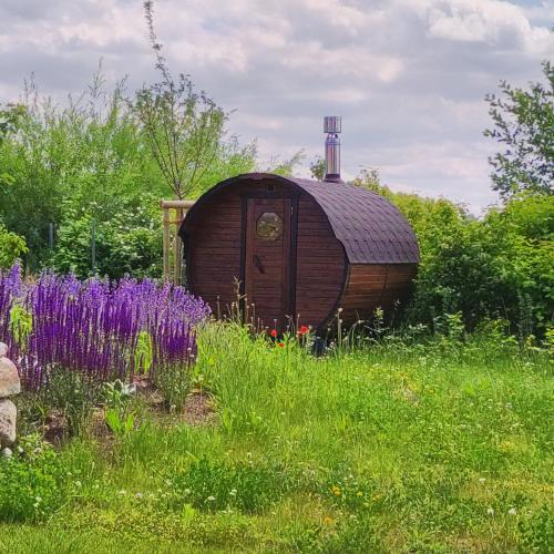 a wooden barrel in a field of grass with purple flowers at Premium Ferienhaus Söss Diek in Groß Schwansee in Kalkhorst