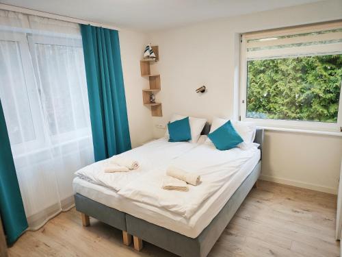 una camera da letto con un letto con cuscini blu e una finestra di Leśny Zakątek a Danzica