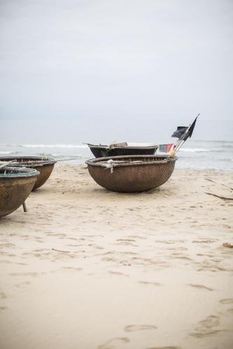 three boats sitting on a beach near the ocean at Dechiu in Hoi An
