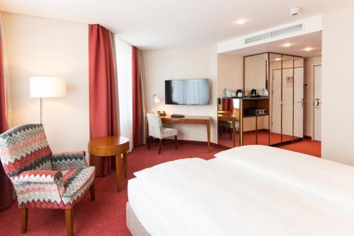a hotel room with a bed and a desk and chair at Best Western Plus Hotel St. Raphael in Hamburg