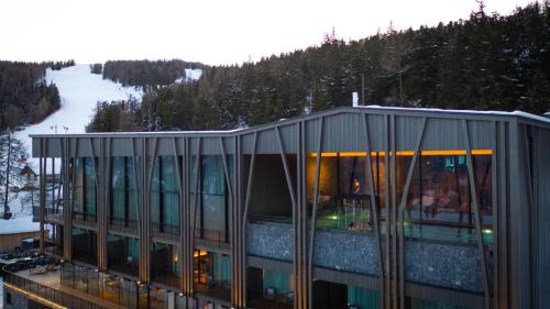 ein Gebäude mit Glasfenstern und einem Berg in der Unterkunft Olangerhof Hotel & Spa in Olang