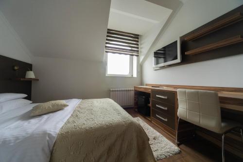 a bedroom with a bed and a desk and a television at Garni Hotel Royal Crown in Subotica