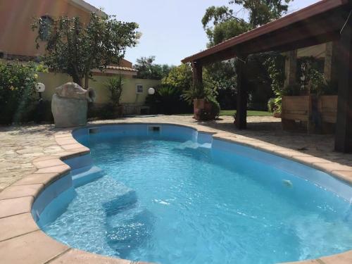 a swimming pool with blue water in a yard at Apartment in Villa, Beach 3 minutes walk, spiaggia 3 minuti a piedi in Su Forti