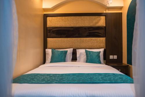 1 dormitorio con 1 cama con almohadas verdes y blancas en Gardens Executive Suites, en Kikuyu