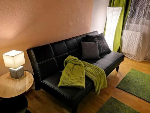 a black leather couch with a green blanket on it at Dachgeschosswohnung am Waldrand in Arzl im Pitztal