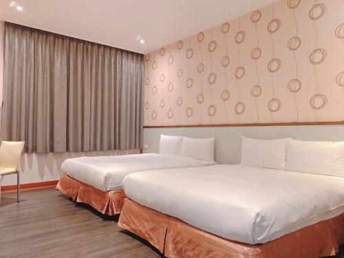 a hotel room with two beds and a window at Zhongshan Boutique Hotel in Kaohsiung