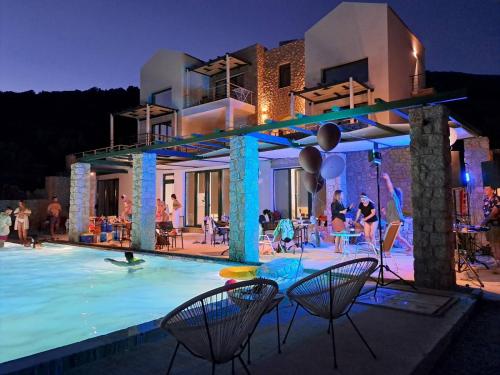 un groupe de personnes dans une piscine la nuit dans l'établissement Karinta Bay Apartments, à Chios