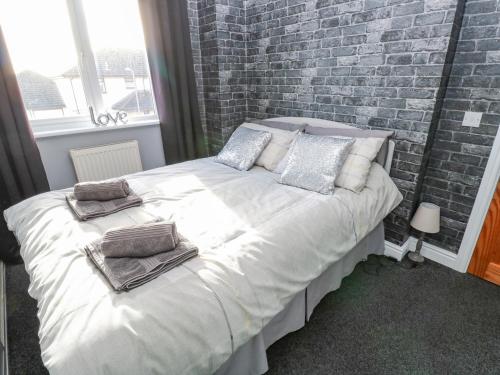 a bedroom with a large white bed with a brick wall at Cherry Tree House in Penzance