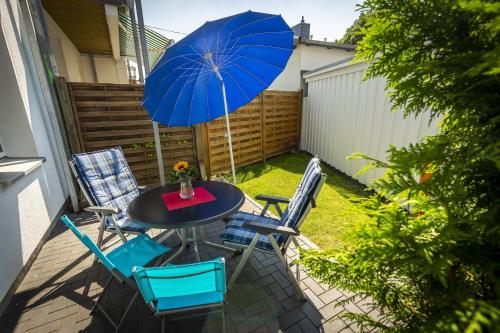 uma mesa e cadeiras com um guarda-sol azul num pátio em Haus Albatros em Timmendorfer Strand