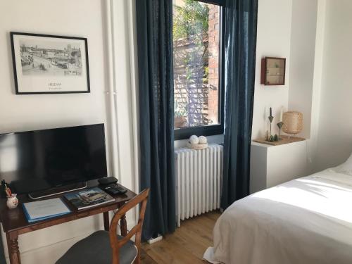 a bedroom with a bed and a desk with a television at LE JARDIN D'ALEXANDRE in Orléans