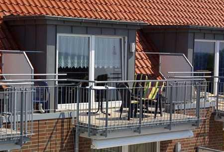einen Balkon mit einem Tisch und Stühlen auf einem Haus in der Unterkunft Nordseewelt Nordseegartenpark in Bensersiel