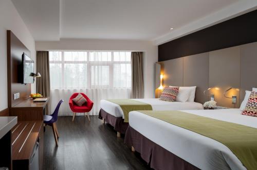 西安市にあるCampanile Xi'an Bell Tower Huimin Streetのベッド2台と赤い椅子が備わるホテルルームです。
