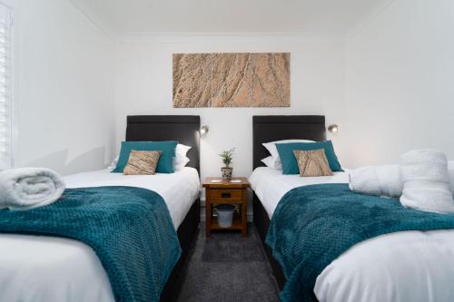 a room with two beds with blue and white sheets at Trevelyan in St Ives