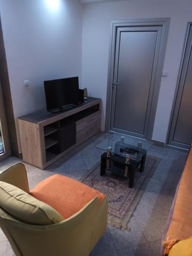 - un salon avec une télévision, un canapé et une table dans l'établissement Apartman Anna, à Kragujevac