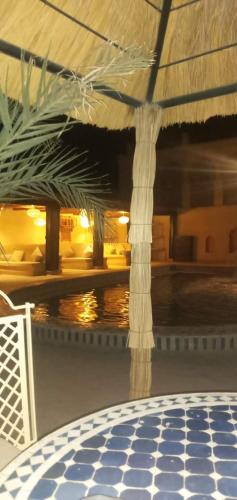 a room with a table and a large umbrella at Kasbah Mohayut in Merzouga