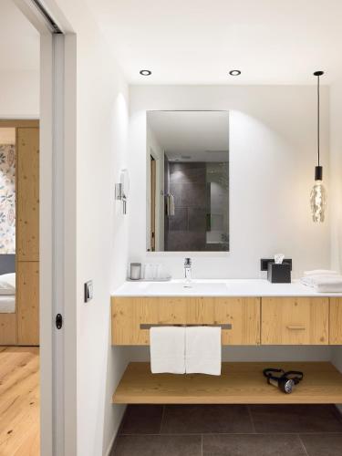 a bathroom with a sink and a mirror at Movi Family Apart-Hotel ****s in Corvara in Badia
