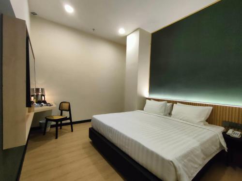 a bedroom with a large bed with a greenboard on the wall at Urban Inn, Alor Setar in Alor Setar
